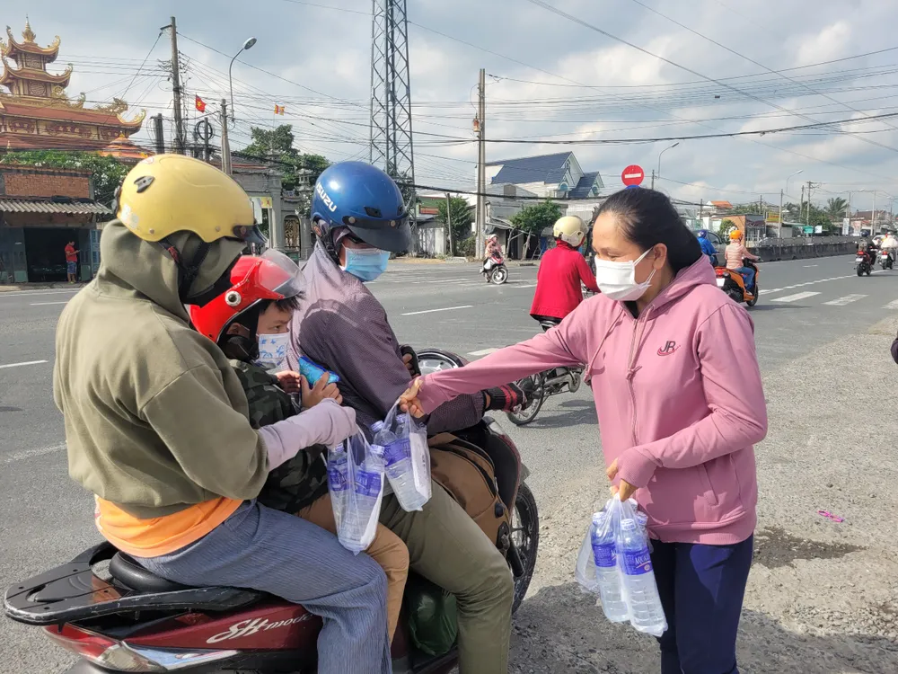 Thành viên nhóm tình nguyện trao nước cho người dân từ miền Tây đi TP.HCM. Ảnh:HD