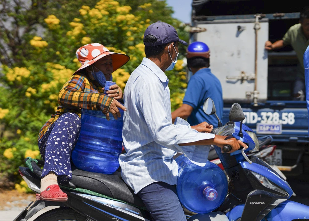 Các bình nước tinh khiết được người dân đem lên xe chở về nhà sử dụng. Ảnh: HD người dân miền hạ (6).JPG