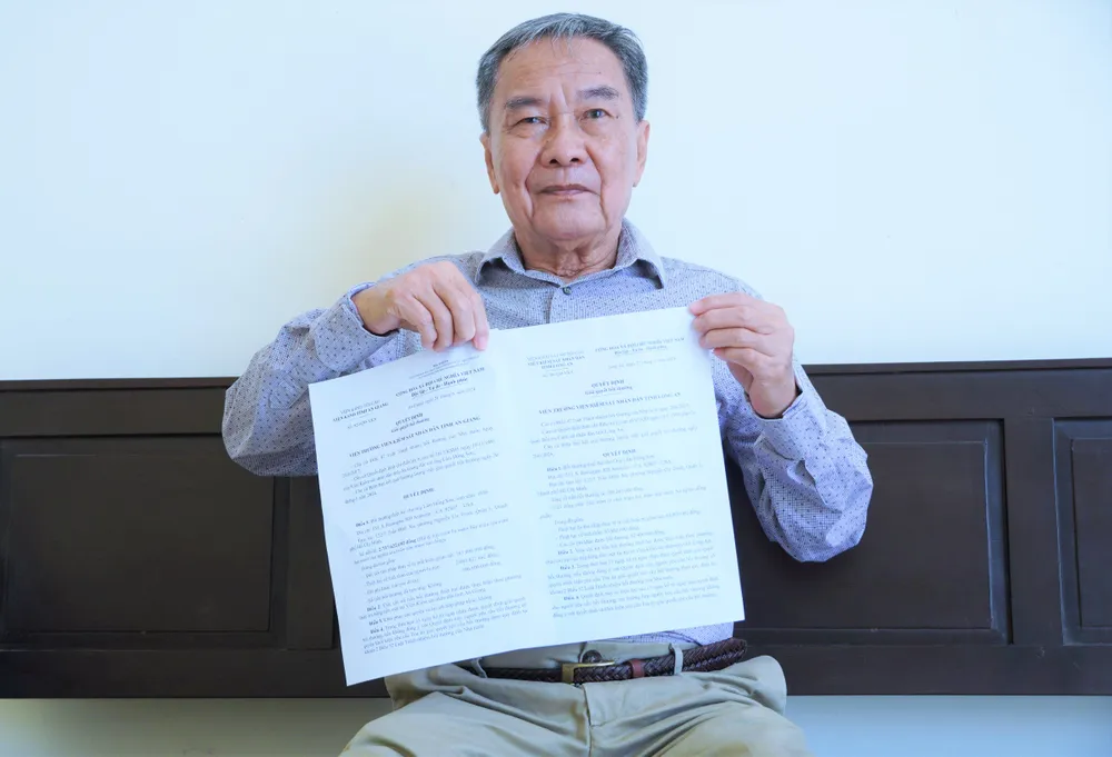 Ông Lâm Hồng Sơn cùng các quyết định bồi thường. Ảnh: HUỲNH DU bị bắt oan 34 năm 1.jpg