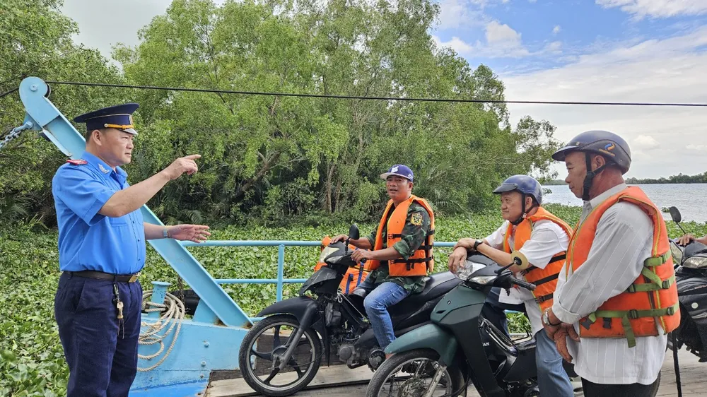 Lực lượng Thanh tra giao thông số 7 nhắc nhở người dân qua phà phải đảm bảo an toàn trong mùa mưa bão. ẢNH: HD mùa mưa bão 6.jpg