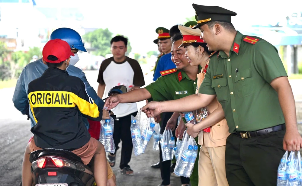 Lực lượng Công an huyện Bến Lức phát nước cho người dân về quê nghỉ lễ Quốc khánh 2-9. Ảnh: VH 1000045103.jpg