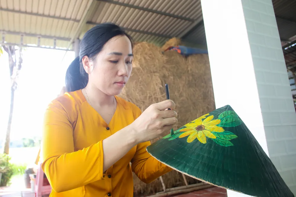 Chị Phạm Thanh Trúc đang vẽ lên chiếc nón những hình ảnh mộc mạc của cảnh đẹp quê hương. Ảnh: HD IMG_9481.jpg