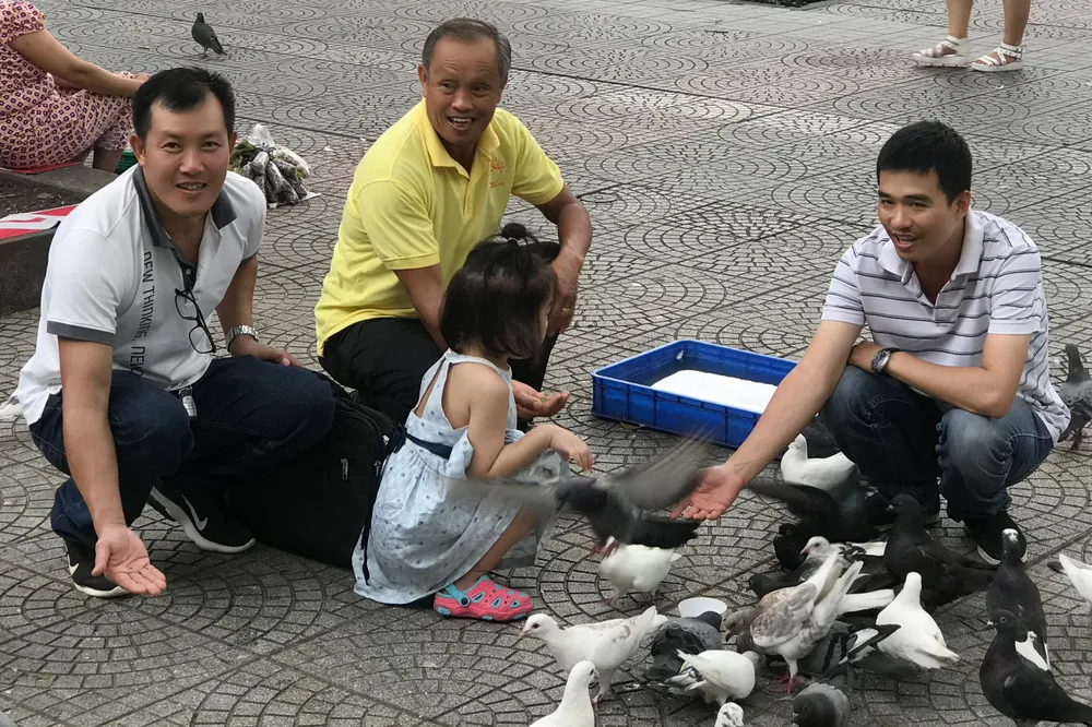 Thích thú khi cho chim bồ câu ăn ngay bên cạnh nhà thờ. Ảnh: HOÀNG HIẾU