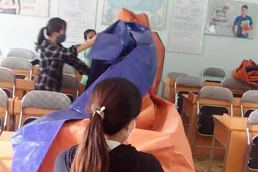 Tháo bạt che bàn ghế để chuẩn bị đón học sinh. Ảnh: HẢI HIẾU