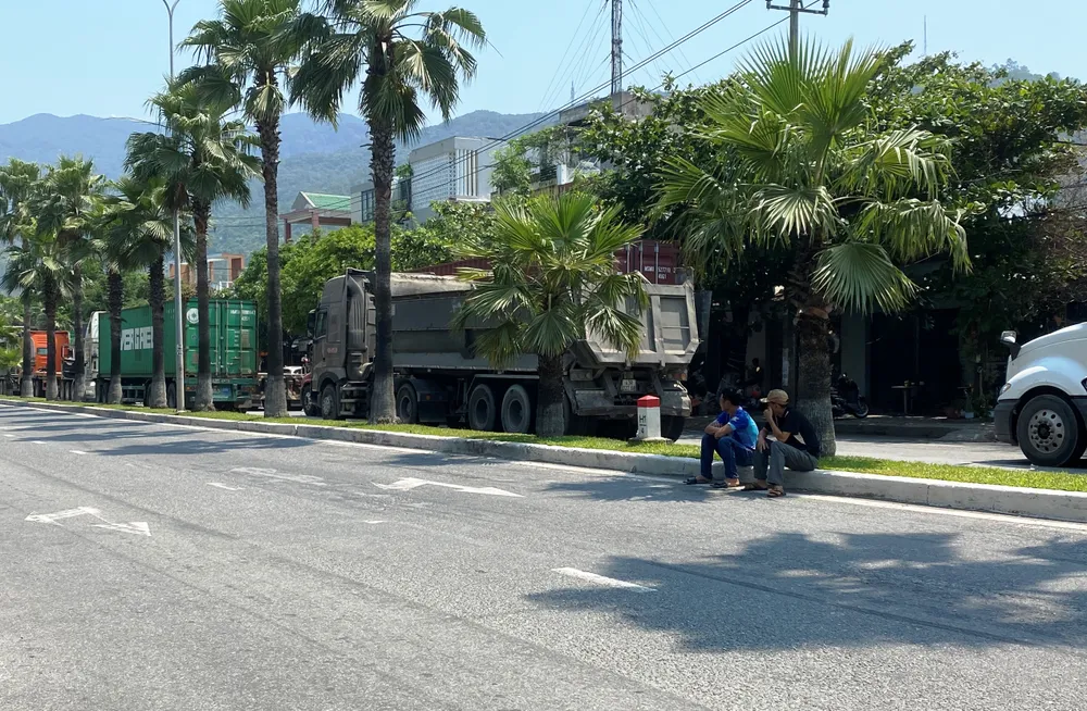 Hai tài xế ngồi ngóng về giao lộ bị chặn, chờ được thông đường. Ảnh: HẢI HIẾU Hai tài xế ngồi ngóng về giao lộ bị chặn, chờ được thông đường. Ảnh: HẢI HIẾU