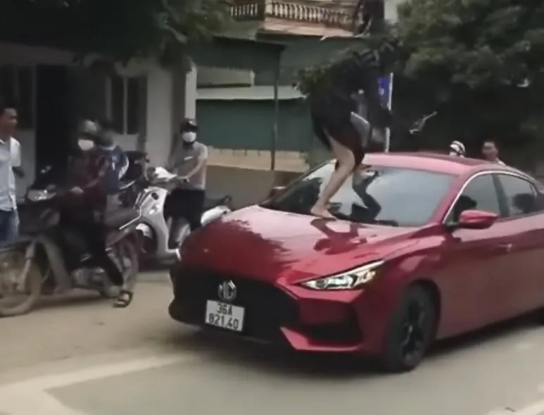 Người phụ nữ đạp vỡ kính xe ô tô được người đi đường quay lại. Ảnh cắt từ clip Người phụ nữ đạp vỡ kính xe ô tô được người đi đường quay lại. Ảnh cắt từ clip