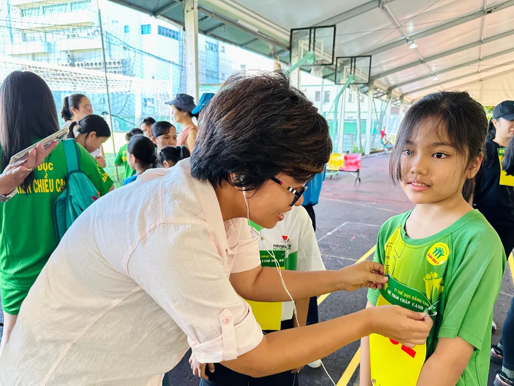 Chị Thanh Tú, ngụ Quận 3, TP.HCM dán mã số dự thi cho con gái để đồng hành cùng các bạn khuyết tật trong cuộc thi. Ảnh: HUỲNH THƠ