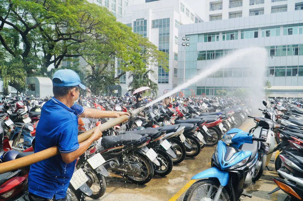 Ông Lê Minh Dũng, nhân viên trường cho biết trước đây sinh viên gặp phải tình trạng xe bị xịt lốp, do nhiệt độ trên sân quá cao, nhưng từ khi triển khai phun nước thì tình trạng này không còn xảy ra. Ảnh: HT