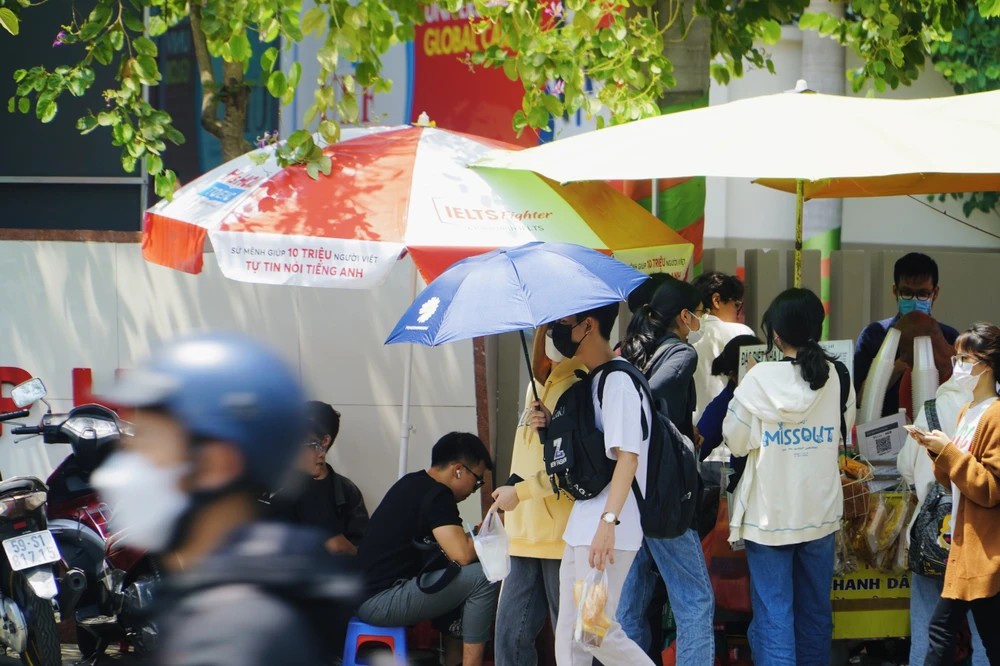Sinh viên dùng dù để che nắng khi di chuyển đến trường. Ảnh: HUỲNH THƠ