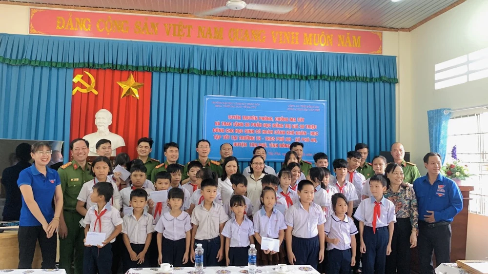 Các cán bộ công an trao học bổng cho các em học sinh. Ảnh: CA