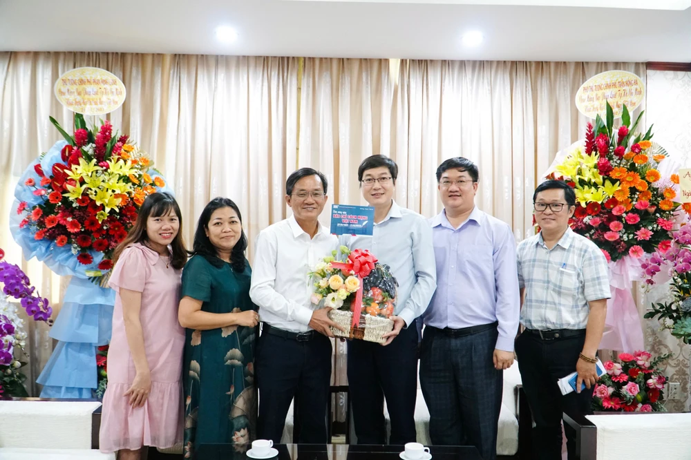 ThS Nguyễn Ngọc Trung, Phó Hiệu trưởng Trường ĐH Sư Phạm TP.HCM trao quà cho báo Pháp Luật TP.HCM. Ảnh: NHẬT DIỄM