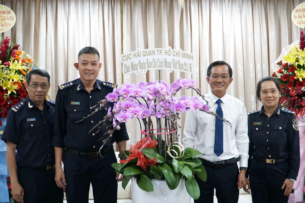 Đại diện Cục Hải quan TP.HCM tặng hoa cho báo Pháp Luật TP.HCM. Ảnh: NHẬT DIỄM