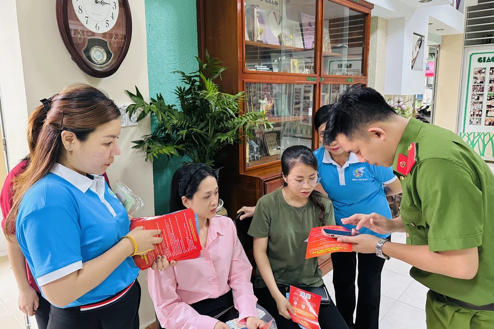 Công an cùng cán bộ hội LHPN phường tích cực hướng dẫn người dân các bước cần thiết trước khi làm thủ tục cấp tài khoản định danh mức 2. Ảnh: HUỲNH THƠ