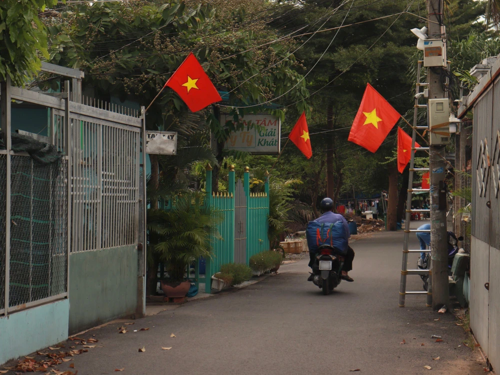 Một đoạn đường nhỏ tại xã Bình Hưng (huyện Bình Chánh) cũng được người dân treo cờ trước nhà để chào mừng 2-9. Ảnh: HUỲNH THƠ
