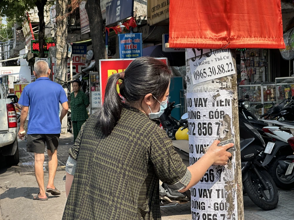 Người phụ nữ dán quảng cáo, tờ rơi ở cột điện bị cảnh sát khu vực bắt cạo, xoá. Ảnh: HUỲNH THƠ 105BC9AD-A596-439F-8915-0E453D0781E3.jpeg