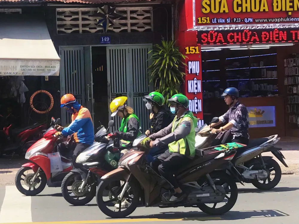 Một số tài xế xe công nghệ vừa chạy trên đường vừa xem điện thoại. Ảnh: HUỲNH THƠ IMG_9535.jpeg