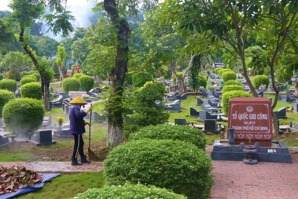 Quét lá, nhổ cỏ, lau chùi bia mộ liệt sĩ và thắp nhang,… là những việc thường ngày của bà Hanh. Ảnh: THẢO PHƯƠNG