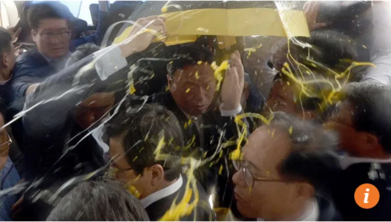 Bảo vệ cố gắng che chắnThủ tướng Hwang Kyo-ahn (giữa) khi ông bị ném trứng. 