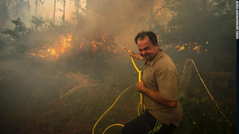 Người dân cố gắng dập lửa tấn công vào vườn nhà mình ở vùng Pontevedra, tây bắc Tây Ban Nha ngày 11-8.