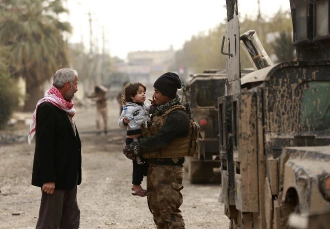 Lính chống khủng bố Iraq và người dân khu vực Mosul tái chiếm được từ IS ngày 13-12. Ảnh: AP 