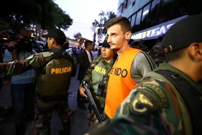 Áp giải nghi can. Ảnh: REUTERS