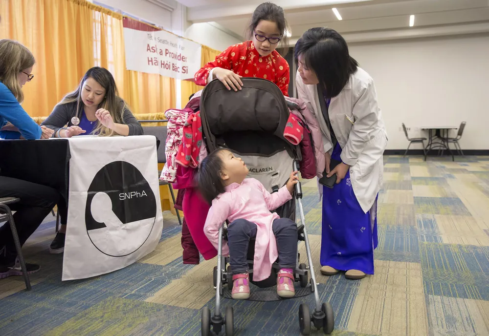 Chị Karen Smith (trái)nhận kết quả kiểm tra sức khỏe tại triển lãm y tế, một phần của chuỗi hoạt động Tet in Seattle ngày 22-1, trong khi các con chị trò chuyện với y tá. Ảnh: SEATTLE TIMES