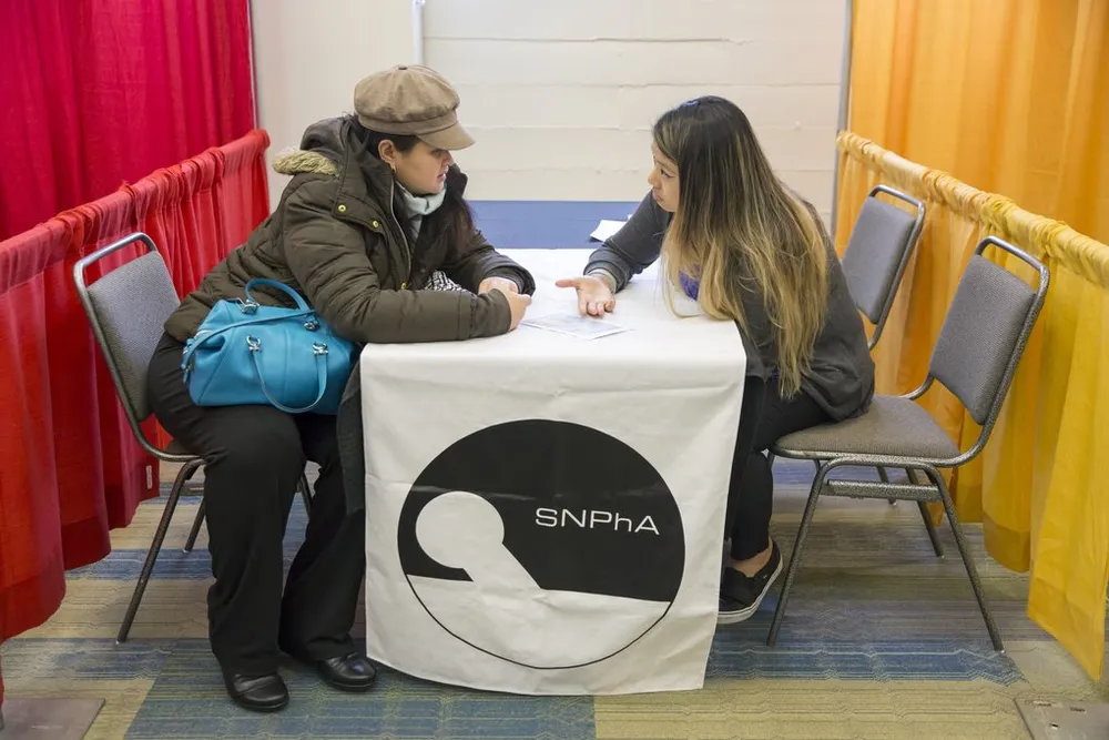 Edna Cusi (trái) được Catherine Nguyễn, một sinh viên dược năm ba tại ĐH Washington, giải thích và tư vấn về kết quả đo cholesterol. Ảnh: SEATTLE TIMES