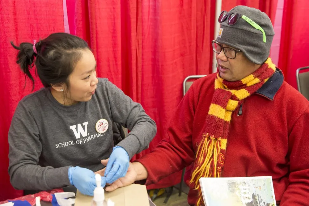 Cecilia Phạm, sinh viên năm nhất tại ĐH Dược Washington, kiểm tra lượng cholesterol và đường trong máu cho ông Jim Kaanana ngày 22-1. Ảnh: SEATTLE TIMES