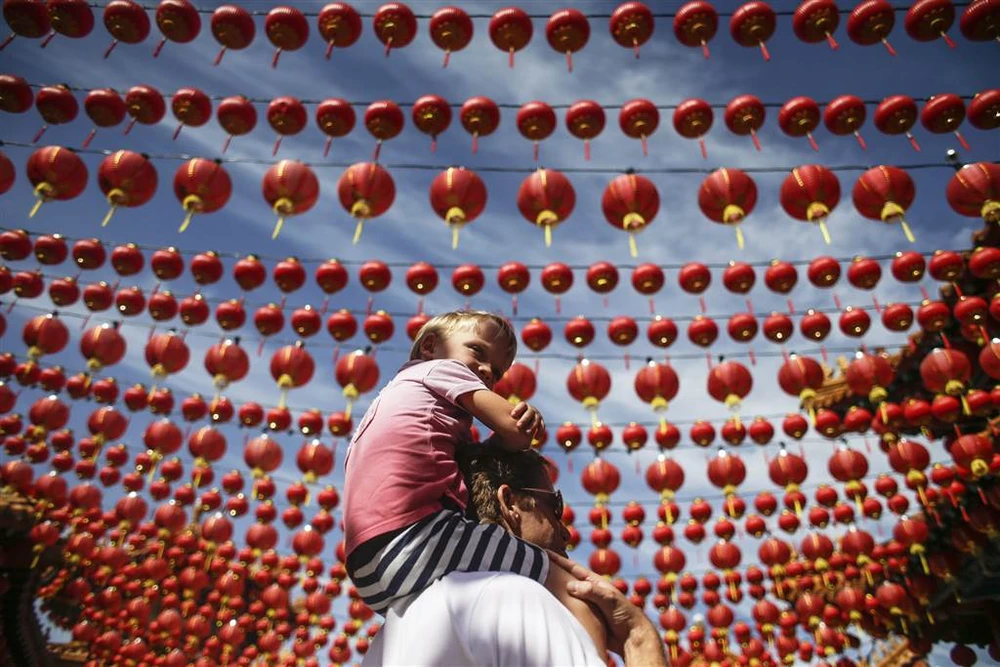 Cha con đi dạo dưới vòm đèn lồng đỏ trang hoàng mừng Tết tại một ngôi đền ở Kuala Lumpur (Malaysia) ngày mùng Một, nhằm ngày 28-1. Ảnh: EPA