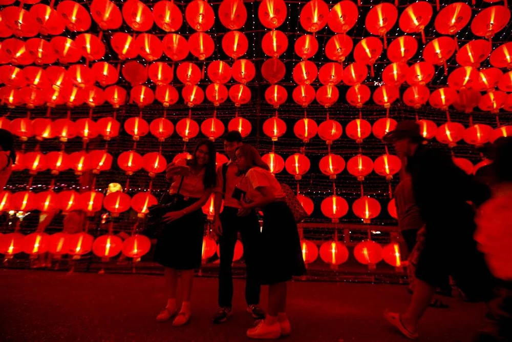 Chụp ảnh lưu niệm trên đường phố trang hoàng đầy đèn lồng đỏ ở Bangkok (Thái Lan) đêm 29 Tết, nhằm 26-1. Ảnh: REUTERS