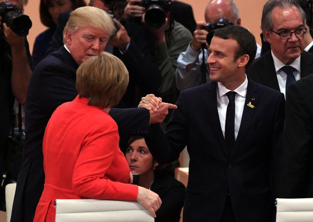 Tổng thống Mỹ Trump (trái) bắt đầu khóa tay Tổng thống Pháp Macron tại G20 trong khi vẫn nói chuyện với Thủ tướng Đức Merkel. Ảnh: NYT