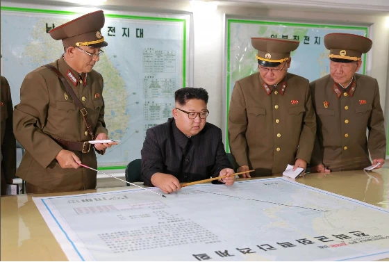 Lãnh đạo Triều Tiên Kim Jong-un (ngồi) được báo cáo về kế hoạch nã tên lửa đảo Guam. Ảnh: REUTERS 