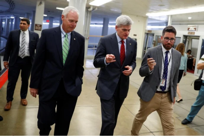 Các thượng nghị sĩ Cộng hòa Bill Cassidy(phải) và Ron Johnson (giữa) trao đổi với báo chí tại tòa nhà Quốc hội ngày 26-9. Ảnh: REUTERS