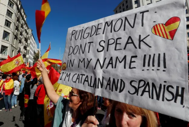 Dân Catalonia mang biểu ngữ “Ông Puigdemont, đừng nói nhân danh tôi”, xuống đường ở Barcelona biểu tình ủng hộ thống nhất, phản đối độc lập, ngày 29-10. Ảnh: REUTERS