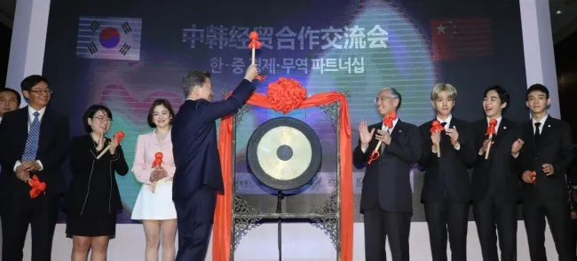 Tổng thống Hàn Quốc Moon Jae-in đánh chuông khai mạc sự kiện Đối tác Kinh tế và Thương mại Hàn-Trung tại Bắc Kinh (Trung Quốc) ngày 14-12, cùng nữ diễn viên Song Hye-kyo và các thành viên ban nhạc EXO. Ảnh: YONHAP