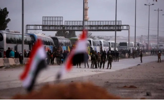 Đoàn xe buýt chở các tay súng nổi dậy Ahrar al-Sham và người thân rời khỏi thị trấn Harasta, Đông Ghouta, ngoại ô Damacus (Syria) ngày 22-3. Ảnh: REUTERS