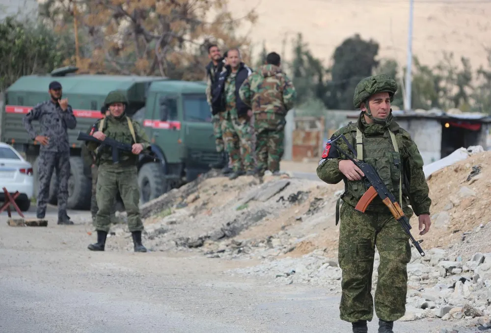 Quân cảnh Nga và binh sĩ Syria tại một chốt kiểm soát gần Đông Ghouta, ngoại ô thủ đô Damascus (Syria) ngày 9-3, thực hiện nhiệm vụ đưa dân thường sơ tán khỏi vùng giao tranh này. Ảnh: AFP