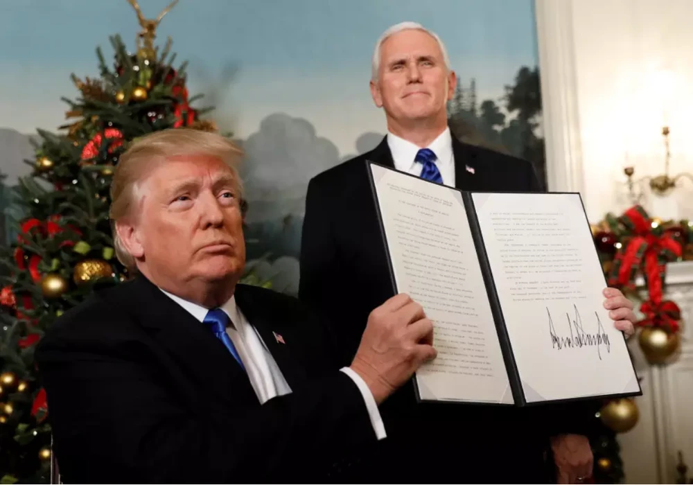 Tổng thống Mỹ Donald Trump (ngồi) giơ cao bản tuyên bố rằng Mỹ công nhận Jerusalem là thủ đô Issael và sẽ di chuyển đại sứ quán đến đây, tại Nhà Trắng ngày 6-12-2017, đứng bên cạnh là Phó Tổng thống Mỹ Mike Pence. Ảnh: REUTERS