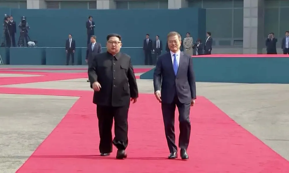 Tổng thống Hàn Quốc Moon Jae-in (phải) và lãnh đạo Triều Tiên bước trên thảm đỏ tiến vào Nhà Hòa Bình bắt đầu cuộc gặp thượng đỉnh. Ảnh: GUARDIAN