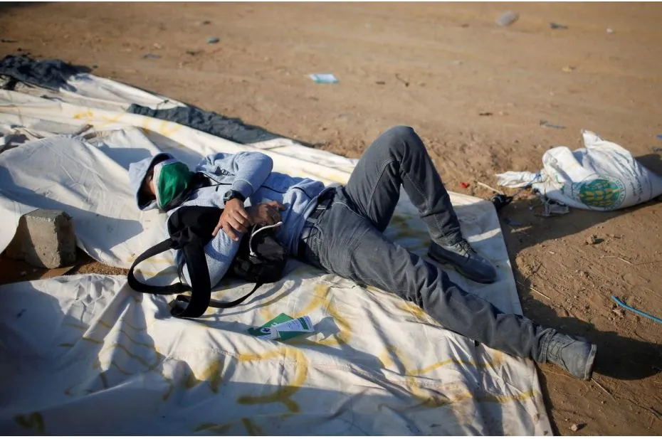 Thanh niên Palestine nghỉ mệt trong khi biểu tình tại biên giới dải Gaza-Israel ngày 14-5, phản đối Mỹ di dời đại sứ quán đến Jerusalem. Ảnh: REUTERS