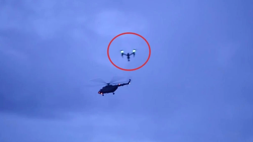 Chiếc máy bay không người lái (trong vòng tròn) bay sát cạnh một trực thăng của quân đội Thái Lan vừa cất cánh chở một cầu thủ nhí vừa được cứu khỏi hang động về bệnh viện. Ảnh: AFP