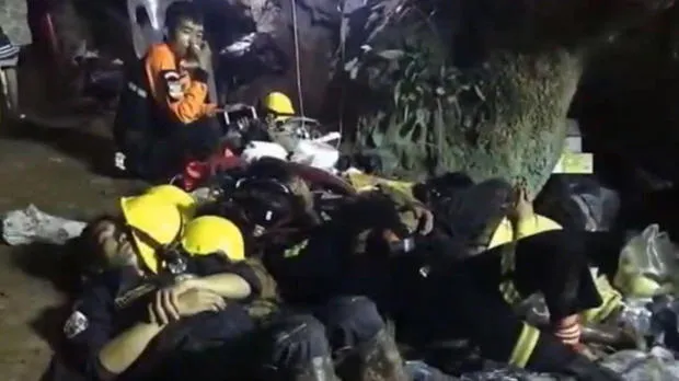 Nhân viên cứu hộ nghỉ mệt ngay trên nền đá trong hang động. Ảnh: CBS NEWS