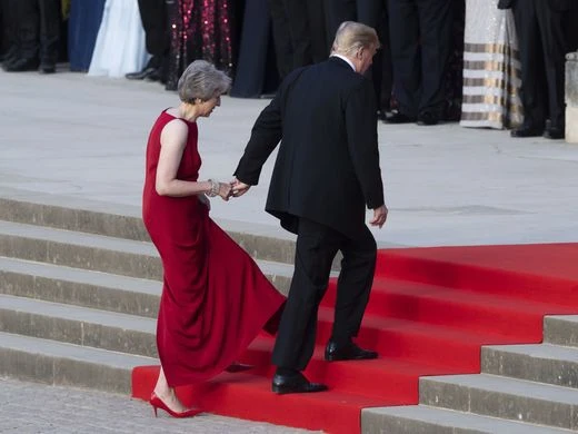 Tổng thống Mỹ Donald Trump đỡ tay Thủ tướng Anh Theresa May bước lên bậc thang vào dự tiệc tối 12-7 Ảnh: GETTY IMAGES