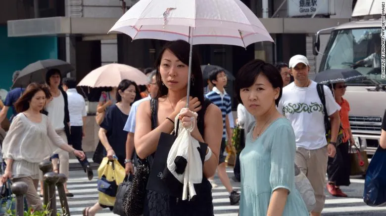 Người đi đường ở Nhật dùng ô tránh ánh nắng mặt trời ở Tokyo, cố gắng hạn chế cái nóng. Ảnh: CNN