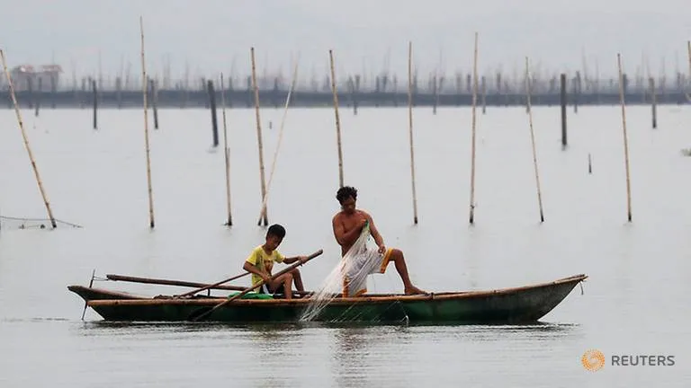 Ngư dân thu lưới trước bão Mangkhut tại khu vực đánh bắt cá ở hồ Laguna de Bay, đảo Luzon (Philippines) ngày 14-9. Ảnh: REUTERS