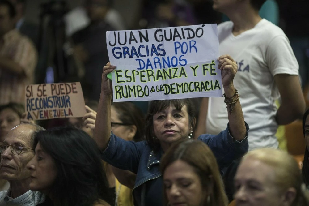 Người ủng hộ tổng thống lâm thời tự xưng Juan Guaido giơ biểu ngữ mang dòng chữ: “Cám ơn Juan Guaido vì đã mang lại hy vọng và niềm tin cho chúng tôi. Chúng ta đang trên đường tiến đến dân chủ”. Ảnh: AP