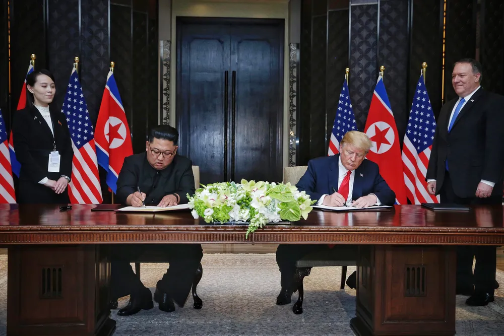 Tổng thống Mỹ Donald Trump (phải) và lãnh đạo Triều Tiên Kim Jong-un ký tuyên bố chung trong cuộc gặp thượng đỉnh đầu tiên ở khách sạn Capella (Singapore) ngày 12-6-2018. Ảnh: AFP