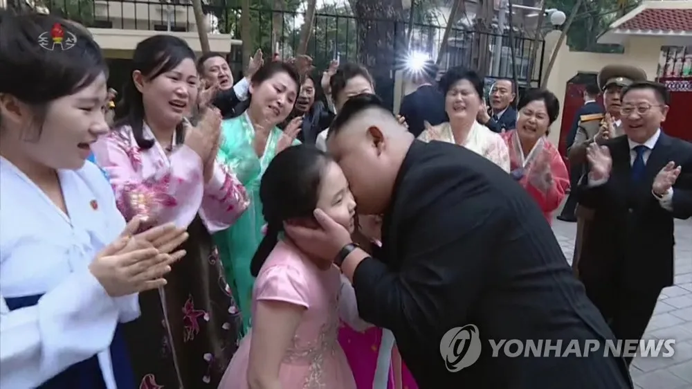 Lãnh đạo Triều Tiên Kim Jong-un hôn má một cậu bé trong lễ đón ông đến thăm Đại sứ quán Triều Tiên ở Hà Nội chiều 27-2. Ảnh: YONHAP chụp lại từ màn hình đài truyền hình trung ương Triều Tiên KCTV