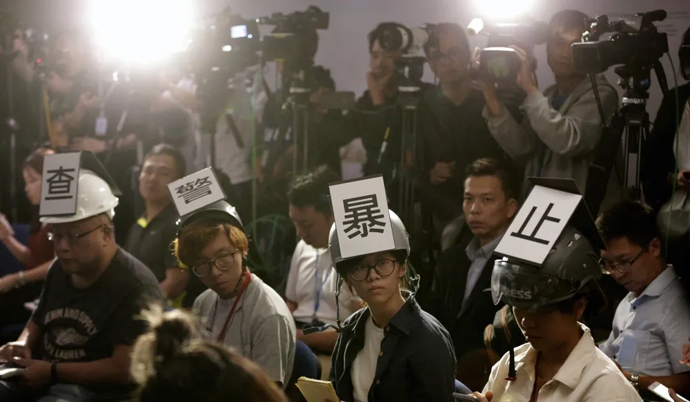 Các nhà báo đội nón bảo hiểm có dòng chữ mang nội dung “Điều tra sự bạo lực của cảnh sát”, phản đối bạo lực của cảnh sát với cánh nhà báo, trong khi tham gia một cuộc họp báo của cảnh sát ở Hong Kong ngày 4-11. Ảnh: AP