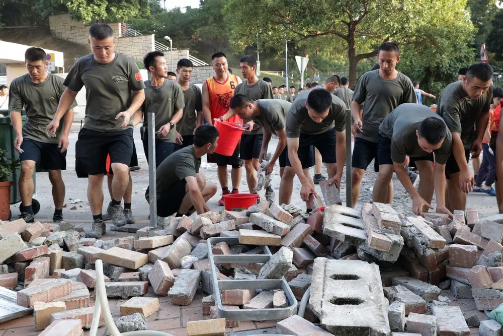 Binh sĩ quân đội Trung Quốc dọn dẹp gạch đá trên đường bên ngoài trường đại học Baptist. Ảnh: SCMP